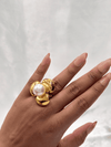 Goldpearl ringElegant cocktail ringMinimalist floral jewelryLustrous pearl ring designWomen’s modern statement ringLuxury gold and pearl accessoryUnique nature-inspired jewelryTimeless pearl statement ringBold gold-tone ringSophisticated women’s jewelryDesigner pearl floral ringContemporary gold jewelry for women